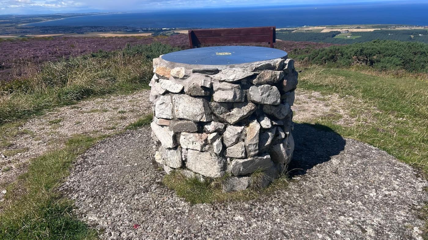 The toposcope on its stone plinth at the summit, with a bench beside it
and the Moray Firth beyond