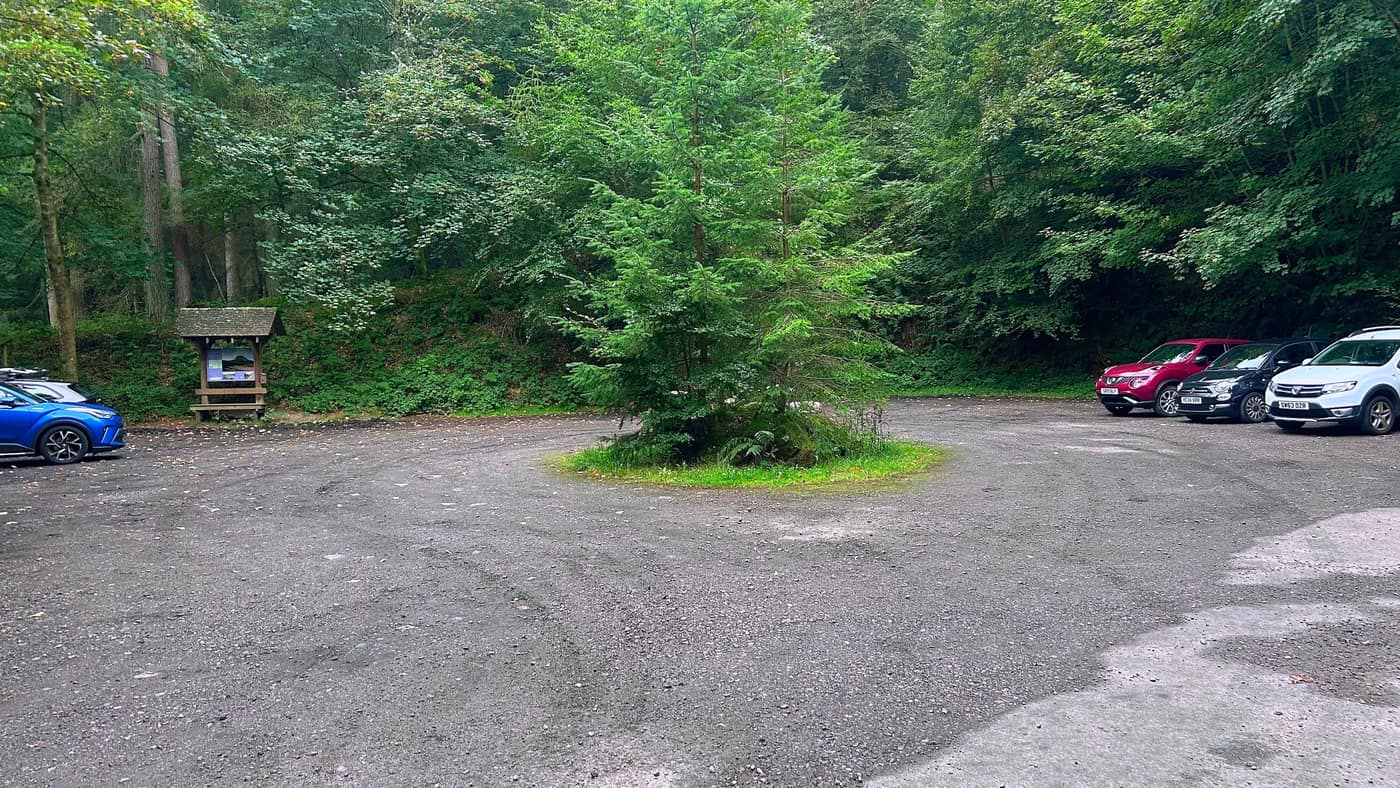 The Glen Dye car park with an information board and a tree in the middle of it