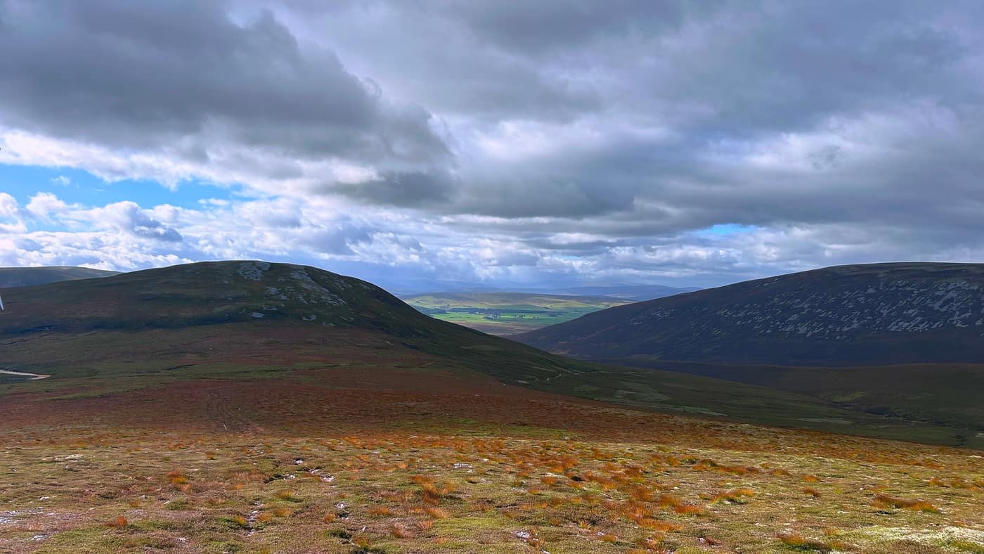 Looking back from the climb, the farmland showing green through the gap in the hills