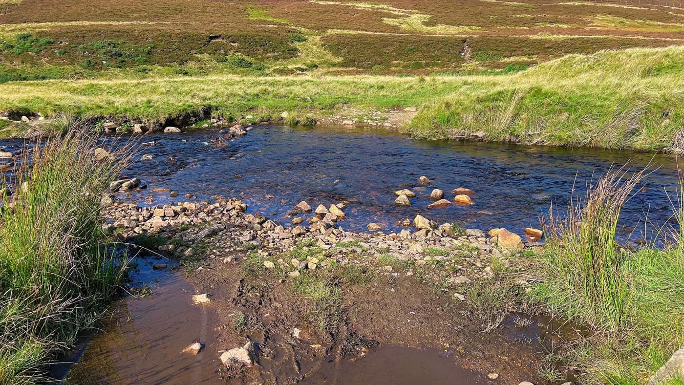 The river crossing — shallow, with stones reaching part of the way over
