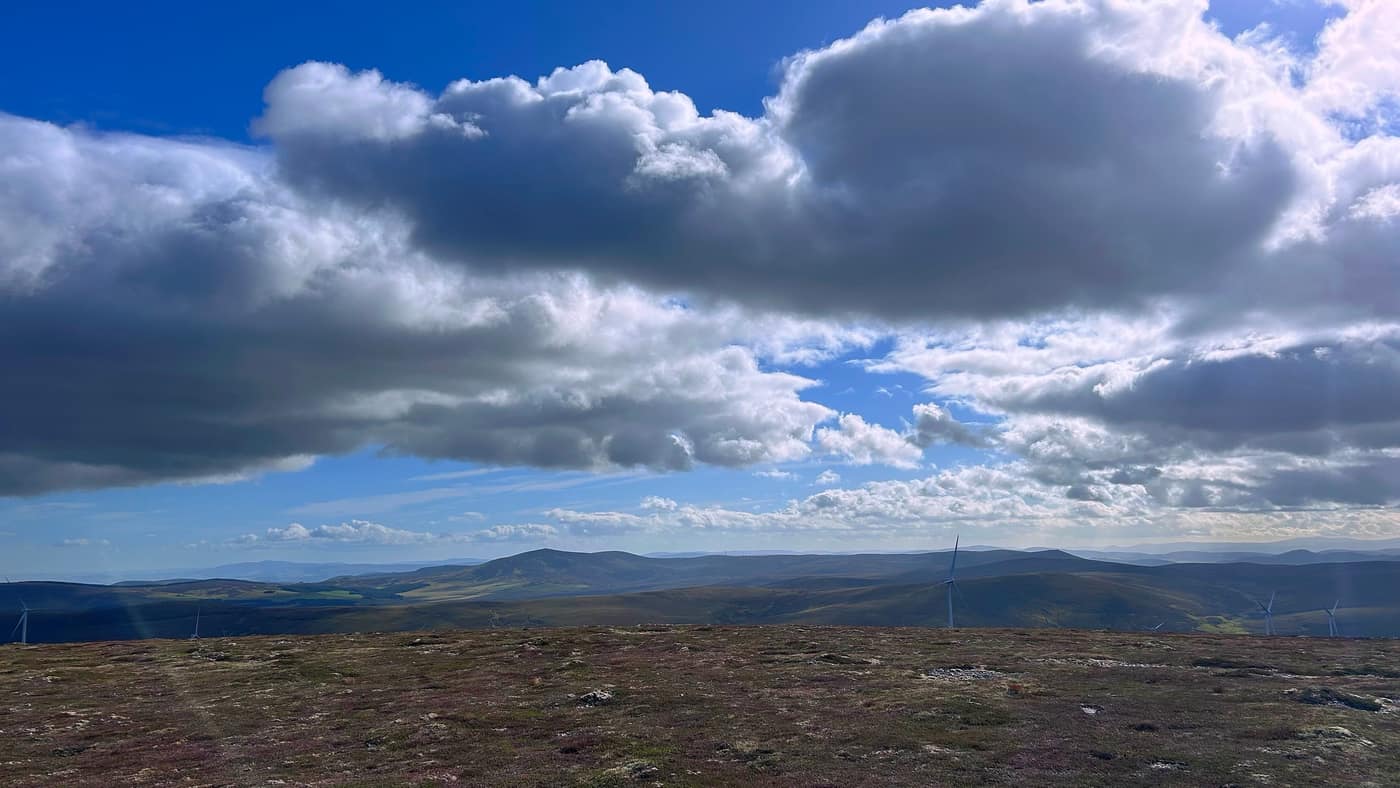 The view from the top, turbines and hills layered away under the cloud