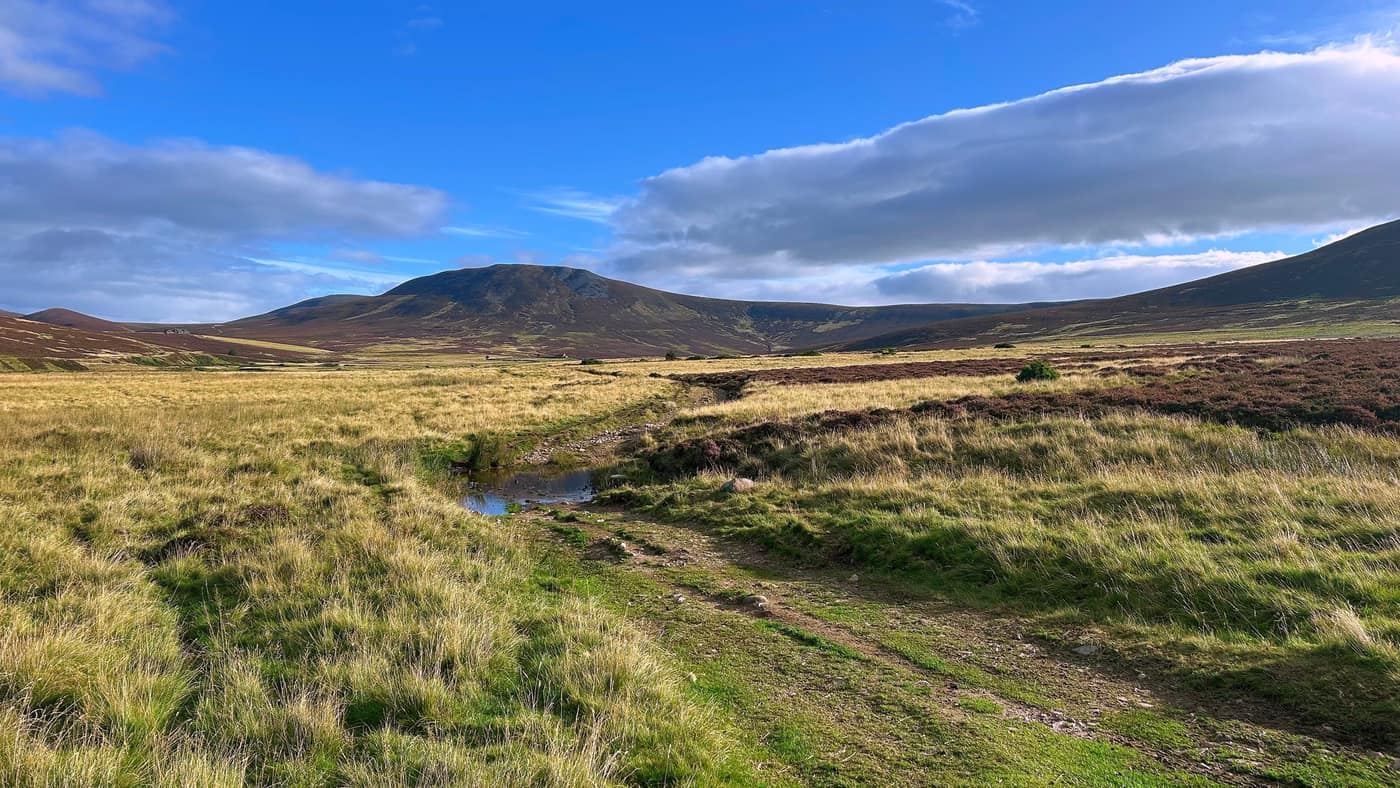 The track heading on towards the hill, a puddle sitting across it