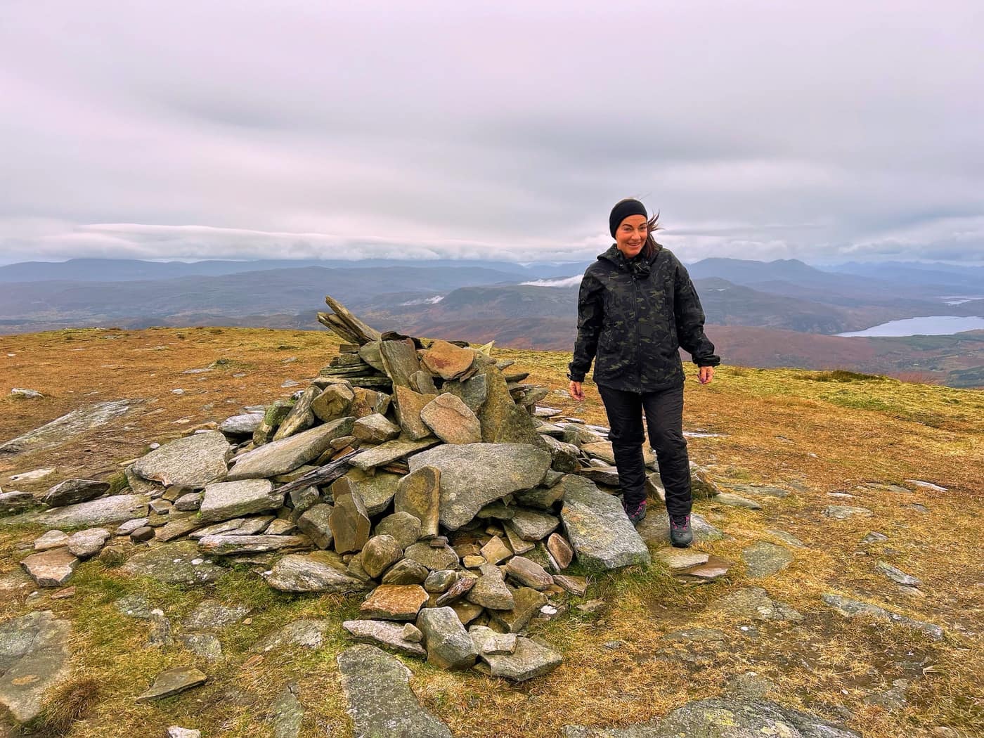 Katrina at the summit cairn, a loch below on the right