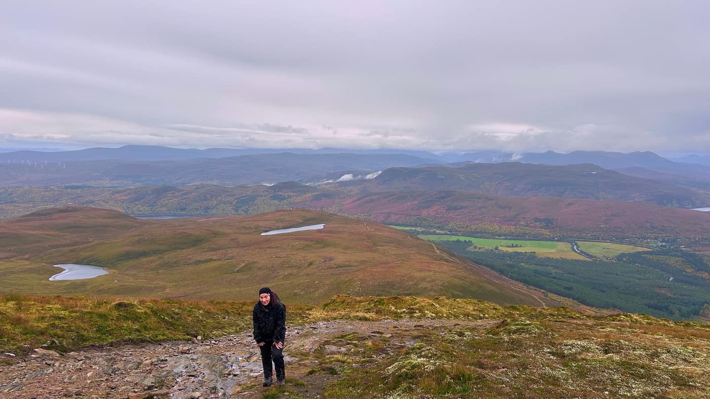 Katrina coming up the last of the path, lochans and hills behind her
