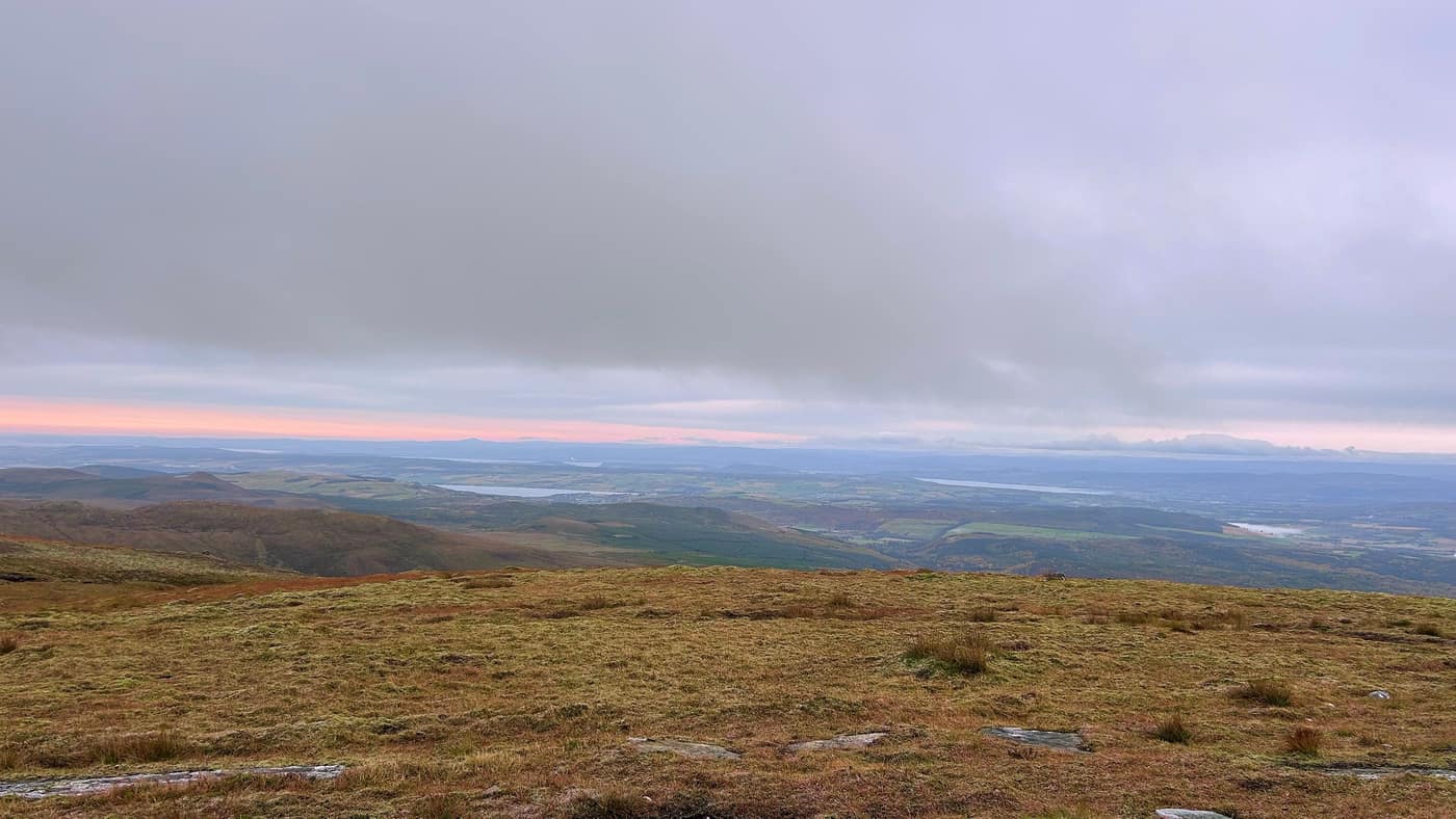 The view east from the summit towards the firths, pink sky low on the horizon
