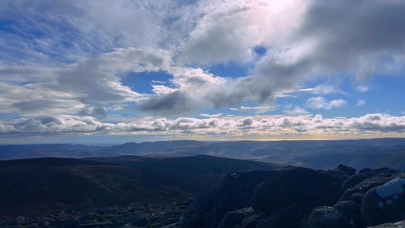 The sun over the hills from the summit rocks, the sea beyond