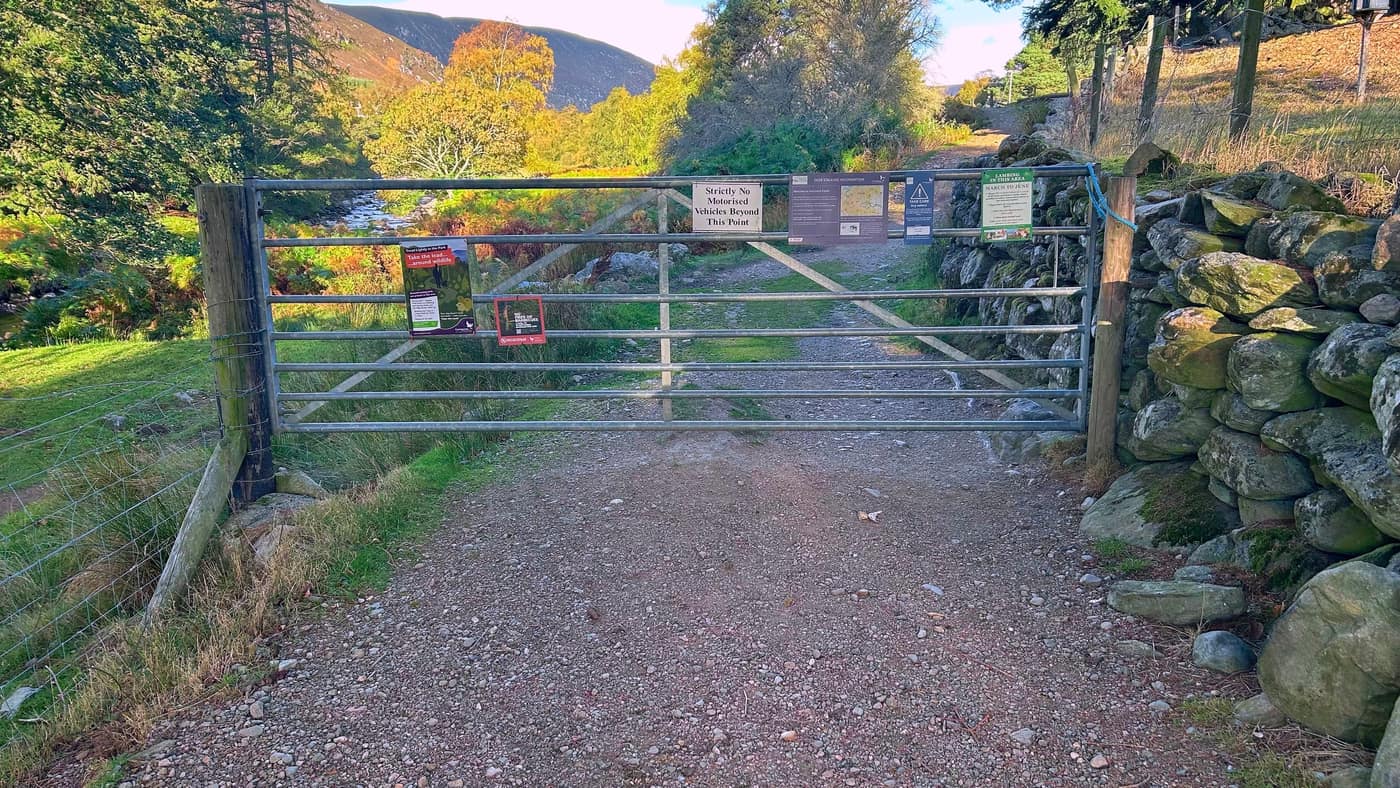 The long metal gate across the track, hung with the estate's notices
