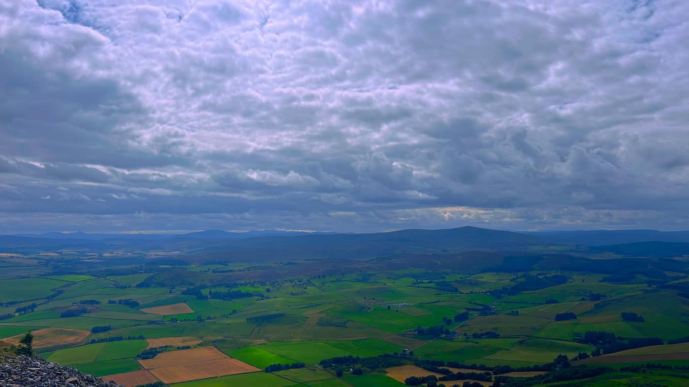 Fields and low hills under a heavy sky