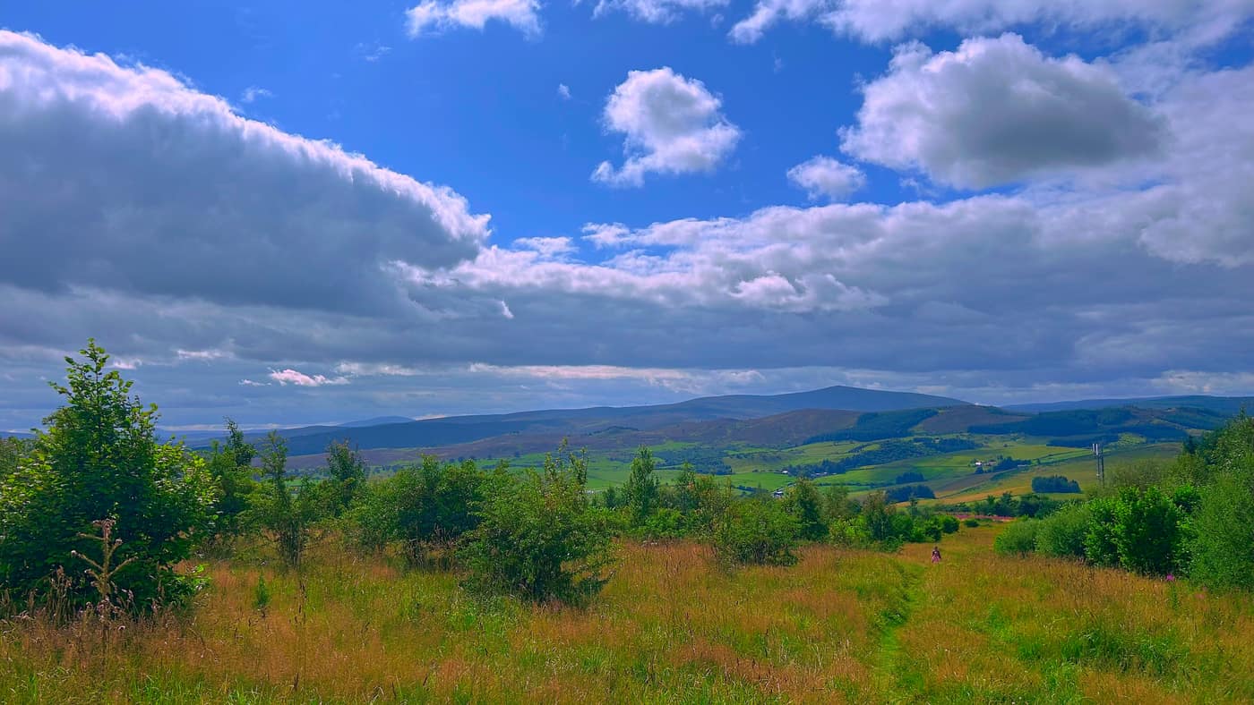 Fields and low hills stretching out from the path