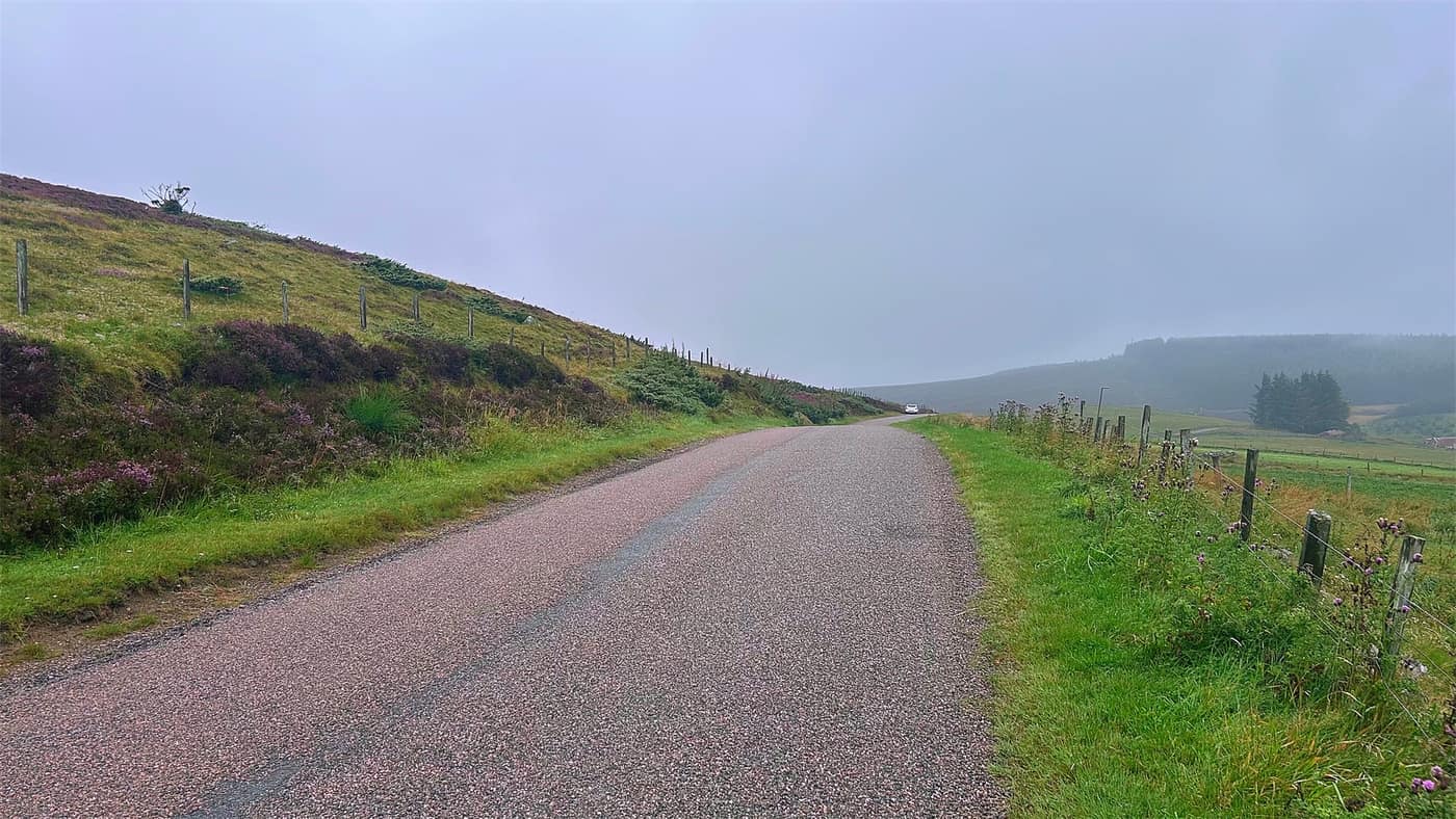 The single track road running up over the moor, a car parked in the layby ahead