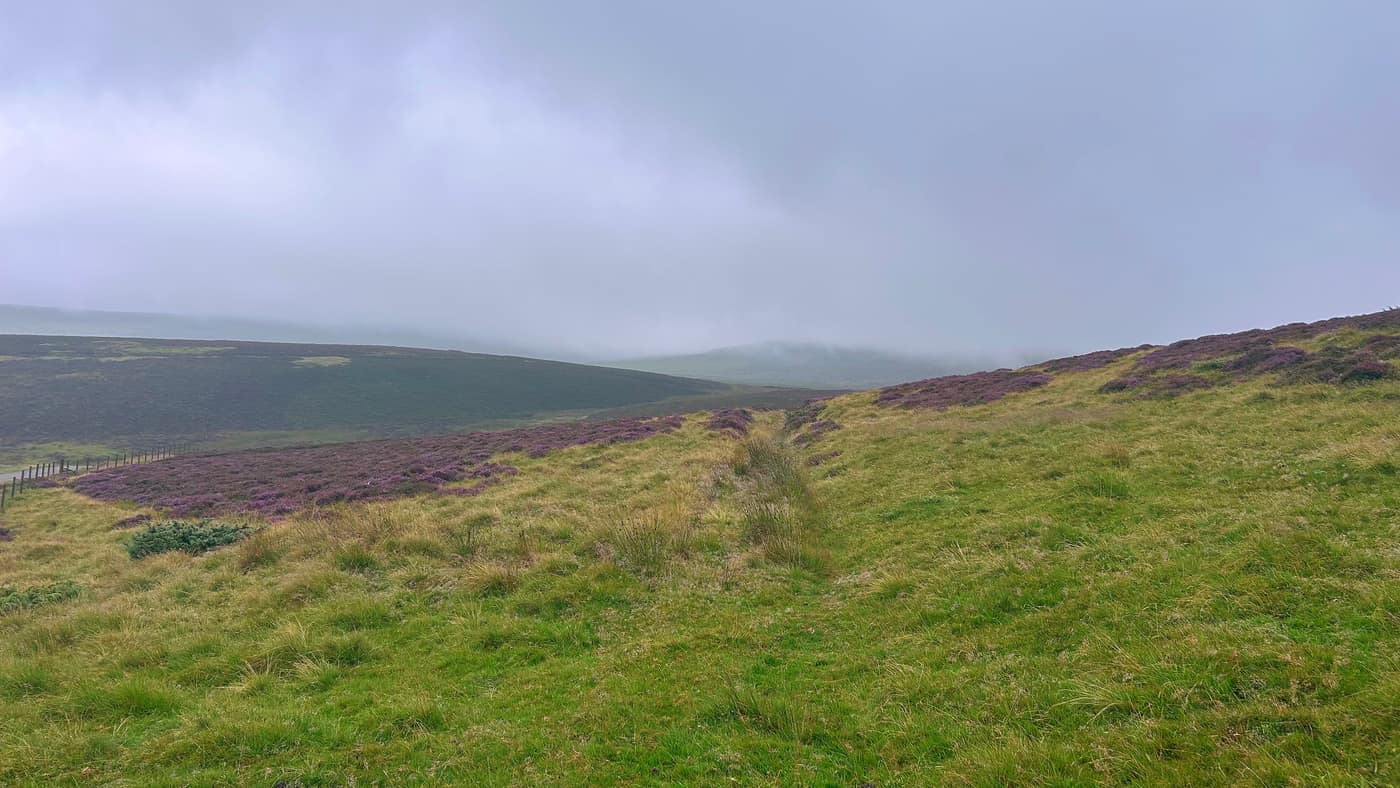 The narrow grass path running out across the moor, hills fading into cloud